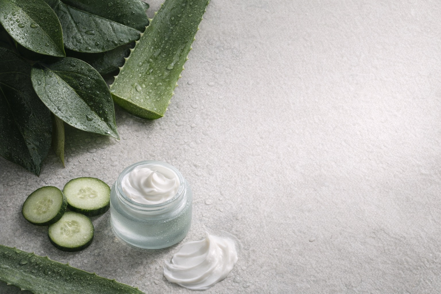Botanical skincare ingredients arranged beside a glass cream jar